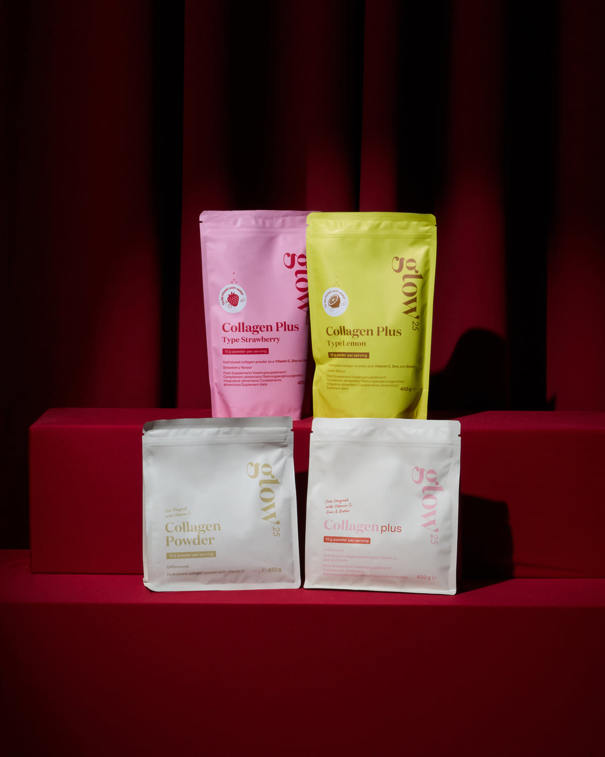 Glow® Cinema: Glow25 Collagen Powder, Collagen Plus, Plus Strawberry and Plus Lemon on a red stage in front of a red curtain