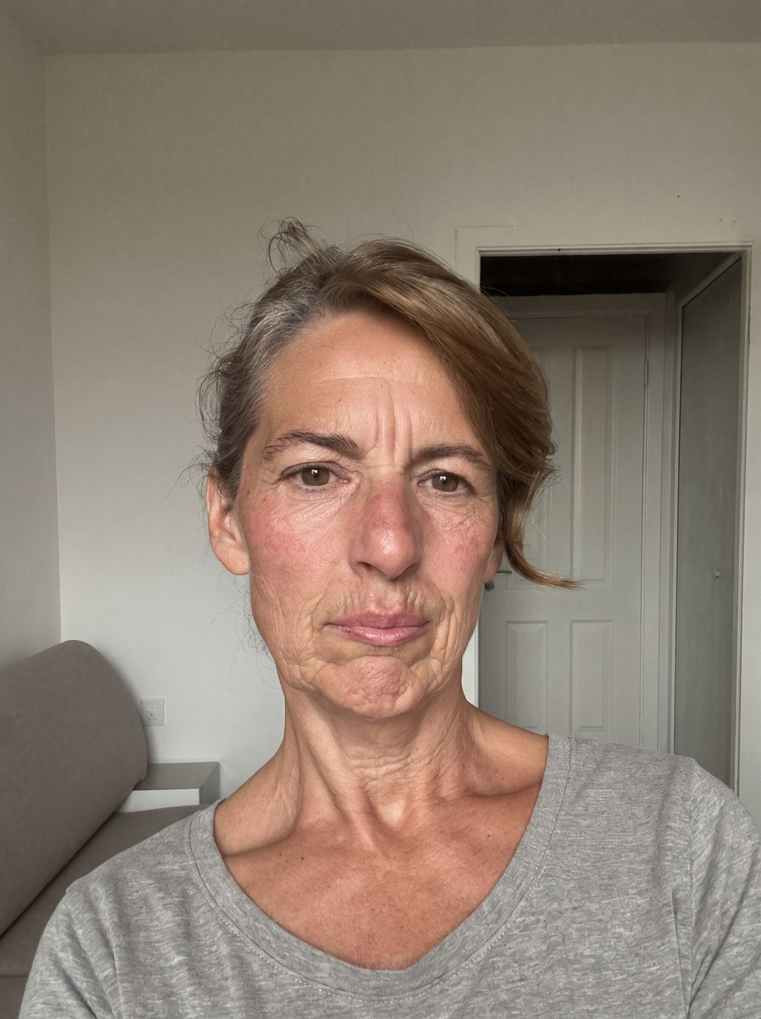 Selfie von Monika, Mitte 50, müde fahle Haut mit tiefen Falten, blickt enttäuscht in die Kamera